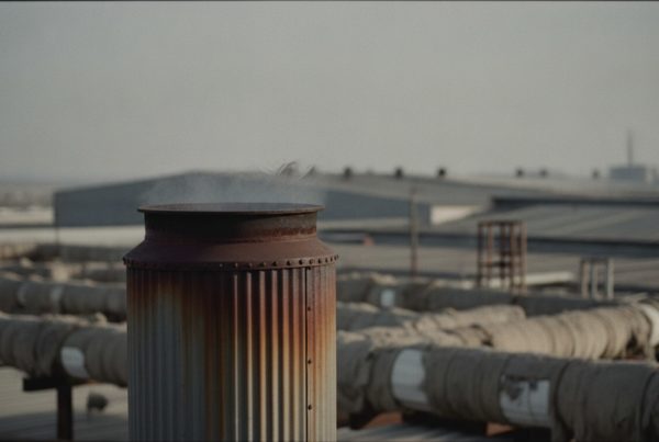 Aire vibrando de calor sobre la chimenea de una caldera industrial: la energía recuperable que un expediente CAE puede monetizar